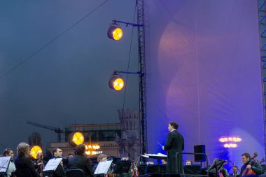 지휘자 배경에 공연 자와 함께 심포니 오케스트라 지휘.