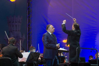 지휘자 배경에 공연 자와 함께 심포니 오케스트라 지휘.