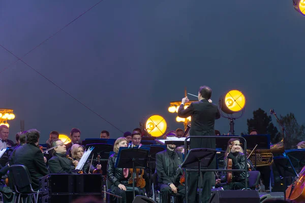 Dirigent dirigiert Symphonieorchester mit Interpreten im Hintergrund. — Stockfoto