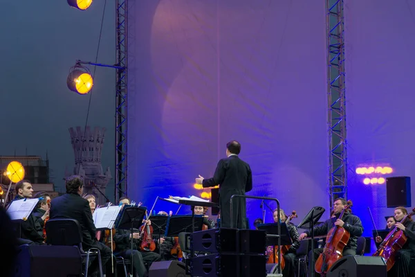 Dirigent dirigiert Symphonieorchester mit Interpreten im Hintergrund. lizenzfreie Stockfotos