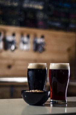 Kırmızı ve siyah bira gözlük ile bir kase fıstık üzerinde ahşap Birahane