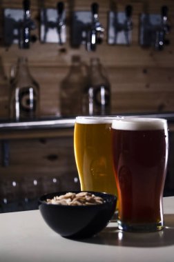 Kırmızı ve sarı bira gözlük ile bir kase fıstık bir tahta üzerinde brewerly