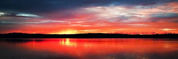 一个引人注目的鼓舞人心的红彩色多云日出海景水与生动的水反射 — 图库照片