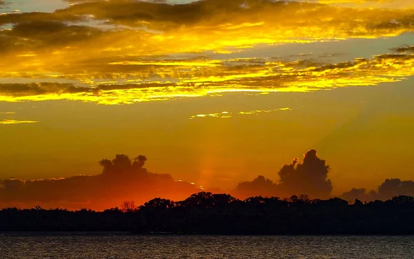 A eye catching inspirational yellow and crimson stratus and cumulus cloud in a grey coloured sky. Vibrant sunset seascape with ocean water reflections. Fraser Island, Queensland, Australia.