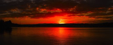 Avustralya yaz deniz manzarası, waterscape, gün batımı ile primariley Cumulus bulutları köpüklü kıyı okyanus sularında yansıyan kırmızı ve koyu gri gökyüzü karşı.