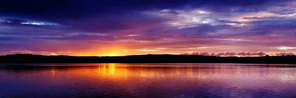 İlham verici bir muhteşem parlak siluetleri okyanus su yansımaları ile featuring altın ve mavi clear deniz su tropik gündoğumu panoramik deniz manzarası renkli. Queensland, Avustralya.
