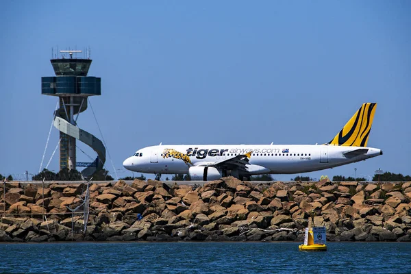 Sidney, Yeni Güney Galler, Avustralya - 7 Kasım. 2013: arası tiger Airways ile ticari yolcu jet uçağı kontrol kulesi canlı mavi Avustralya gökyüzü Kingsford Smith Uluslararası Havaalanı Pist üzerinde geçmiş vergi.