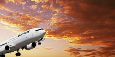 Sidney, Yeni Güney Galler, Avustralya - 9 Kasım. 20116: hava Qantas ticari yolcu jet uçağı efendim Kingsford Smith Airport, Mascott yaklaşıyor. Turuncu renkli altocumulus bulutlu gün batımı gökyüzü ile.