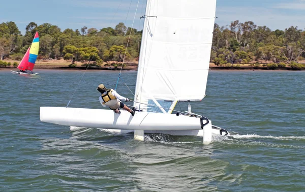 Juventud Vela pequeño barco catamirano con una vela blanca en un inlan — Foto de Stock