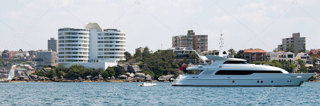  Luxury motor yacht at anchor in North Harbour, with waterfront apartments in the background. Sydney Harbour, Sydney, NSW, Australia.