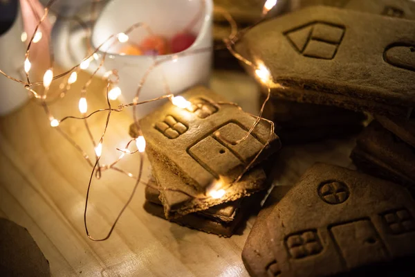 Gingerbread ev duvarları ve ışıklı Noel masanın üzerine döşeme parçaları 
