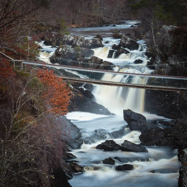 Black Water river in Scottish Highlands - the area of Rogie Falls near Tarvie. Suspended bridge above water.