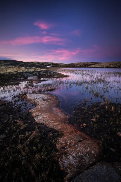 Midnight light in summer time, middle Norway. Light reflections on the surface of small mountain lake.