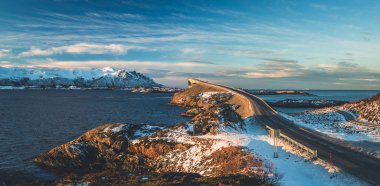 Atlantic Ocean Road - kış güneşli günde Atlanterhavsvegen. Denizin üzerinde ünlü yüksek köprü adı Storseisundbrua ve karlı dağlarda güzel bir ufuk.