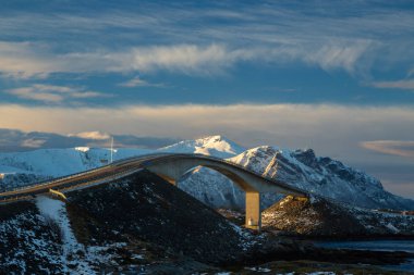 Atlantic Ocean Road - kış güneşli günde Atlanterhavsvegen. Denizin üzerinde ünlü yüksek köprü adı Storseisundbrua ve karlı dağlarda güzel bir ufuk.