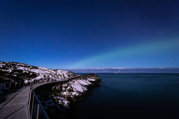 North lights Aurora Borealis seen from Atlantic Ocean road in winter night. Norwegian wintertime. Nice starry sky and green lights.