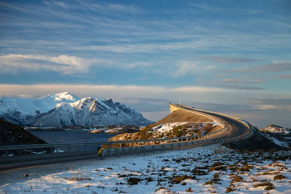 Atlantic Ocean Road - kış güneşli günde Atlanterhavsvegen. Denizin üzerinde ünlü yüksek köprü adı Storseisundbrua ve karlı dağlarda güzel bir ufuk.