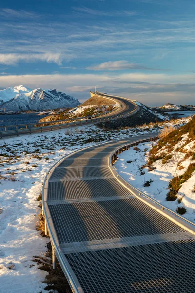 Atlantic Ocean Road - kış güneşli günde Atlanterhavsvegen. Denizin üzerinde ünlü yüksek köprü adı Storseisundbrua ve karlı dağlarda güzel bir ufuk.