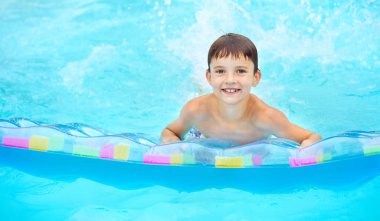 Renkli bir salda yüzen küçük bir çocuk. Yüzme yardımcıları ve çocuklar için giysi. Su oyuncakları.