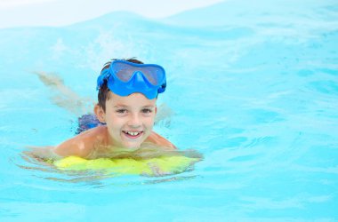 Çocuk tropikal tatil köyü havuzunda yüzmeyi öğreniyor. Çocuklar yüzmeyi öğrenir. Küçük çocuklar için egzersiz ve eğitim