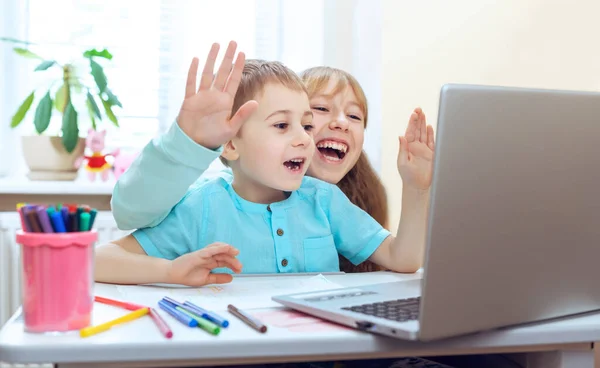 动情的肖像画女孩和男孩坐在房间里的桌子旁 用电脑做作业 用笔记本电脑进行远距离交流 — 图库照片