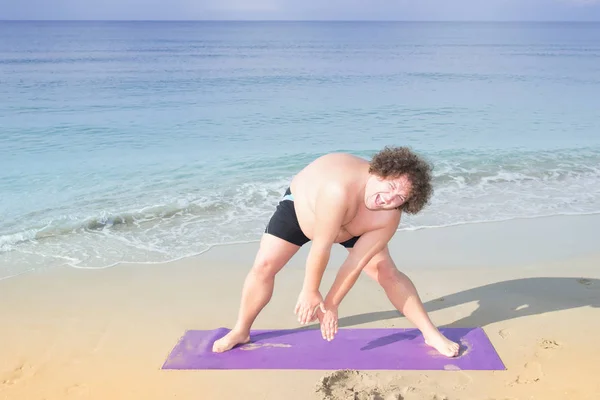 Funny fat man on the sea. Training and healthy lifestyle. Yoga on the beach