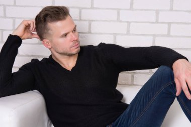 Genç yakışıklı adam dinleniyor. Gömleksiz adam kanepede oturuyor. Kas ve seksi