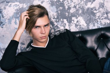 Genç, çekici bir adam. Okuldan sonra konfor. Gri duvar.