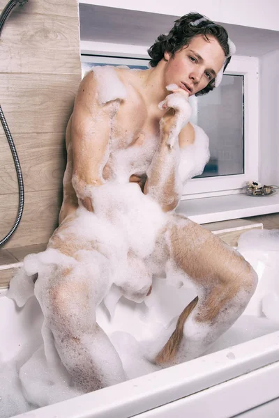 Attractive man in the bath with foam.