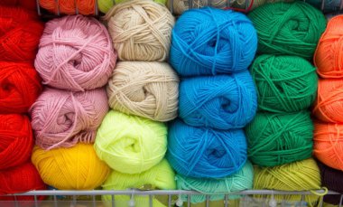 Çok renkli iplik. İplik bej, kahverengi, gri ve beyazdır. Örgü iğneleri, makas, kahve, örgü, örme kumaş.