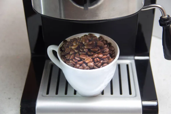 Kaffeebohnen in einer weißen Tasse. Zubereitung von Kaffee. — Stockfoto
