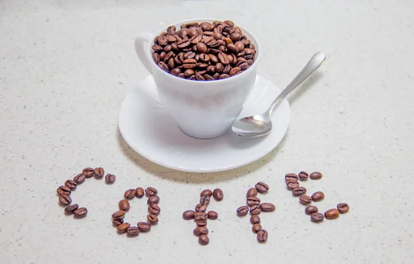 Kaffeebohnen in einer weißen Tasse. verstreute Kaffeebohnen — Stockfoto