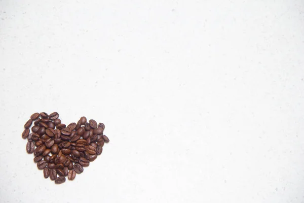 Verschüttete Kaffeebohnen. Kaffee in Herzform. — Stockfoto