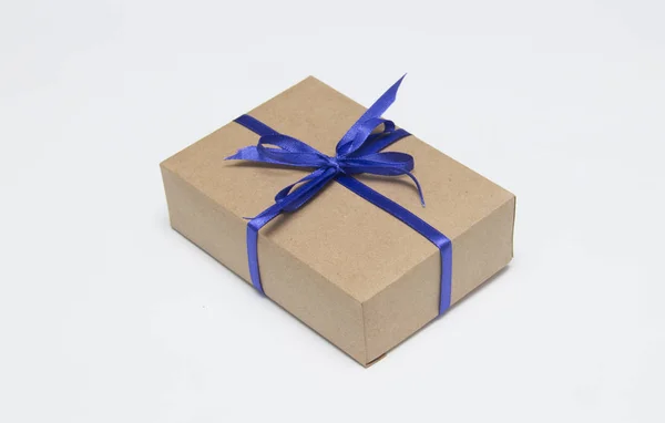 Kraft gift box met blauw lint is op een witte achtergrond — Stockfoto