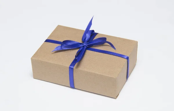 Kraft gift box met blauw lint is op een witte achtergrond — Stockfoto