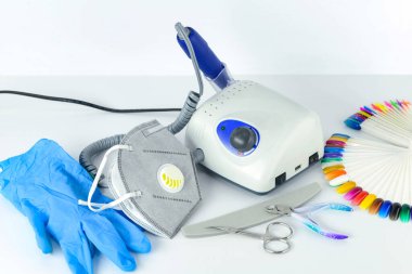Manikür aletleri ve ekipmanlar. Tıbbi maske ve lastik eldivenler manikür makinesinin yanında duruyor..
