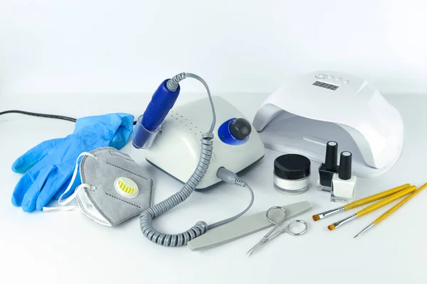 Manicure tools and equipment. A medical mask and rubber gloves lie next to the manicure machine. — Stock Photo, Image