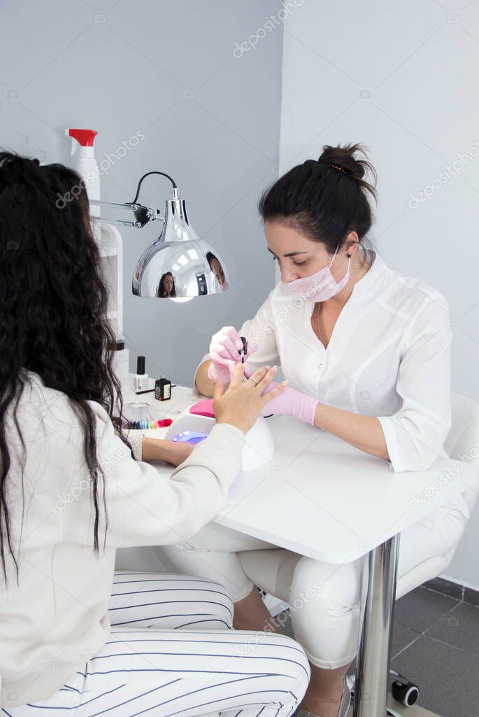 Portrait of an attractive nail salon worker giving a manicure to one of her regular customers