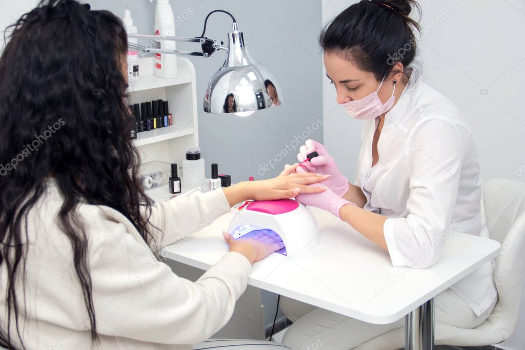 Portrait of an attractive nail salon worker giving a manicure to one of her regular customers