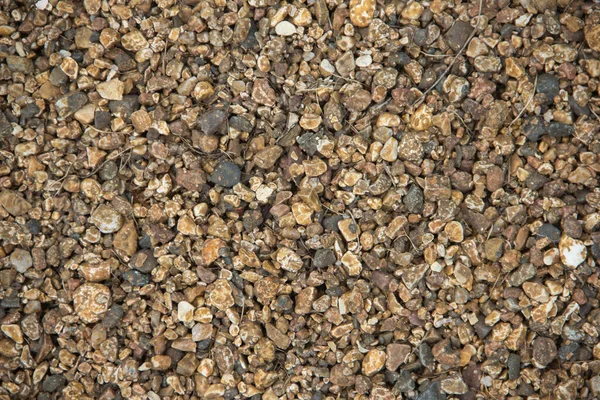 Small stones of seamless texture. Seamless surface texture covered with small dark brown stones.