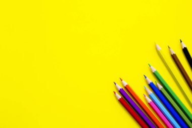 Sarı arkaplanda renkli kalemler.