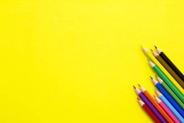 Sarı arkaplanda renkli kalemler.