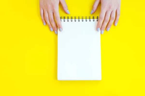 Sarı arka plan üzerinde defter tutan kadın el.