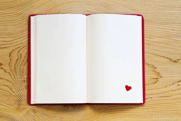 ahşap arka plan üzerinde kırmızı kalpli Not defterini açtınız. üstten görünüm.