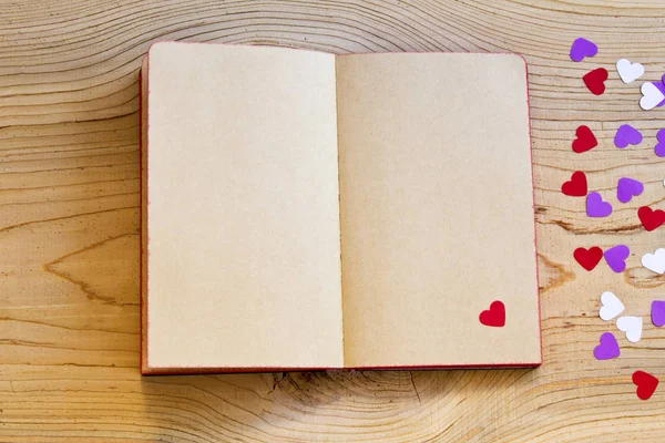ahşap arka plan üzerinde kırmızı kalpli Not defterini açtınız. üstten görünüm.