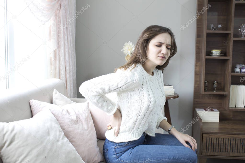 Beautiful young woman suffering from backache at home