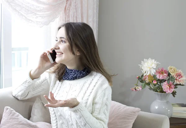 telefonla konuşurken evde kanepede oturan oung mutlu kadın