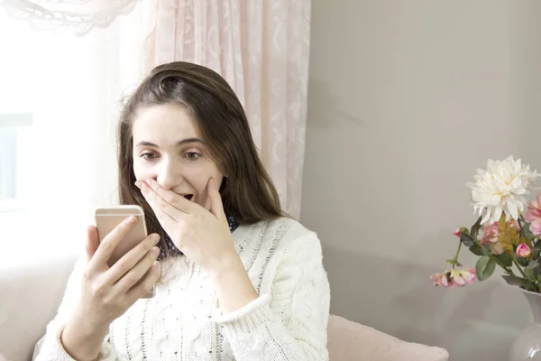 Confuset kız evde bir kanepede oturan bir akıllı telefon bir mesaj okuma