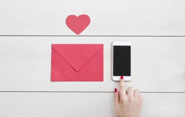 Red envelope, heart and phone on white desk.Valentine day concept.