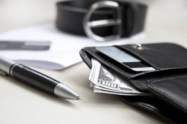 Belgeler, kalem, kemer ve ahşap bir masa üzerine deri cüzdan.